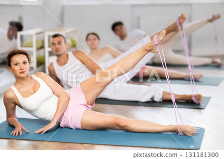 Young woman practicing leg lift with band on feet lying on the side Young woman practicing leg lift with band on feet lying on the side 131181300