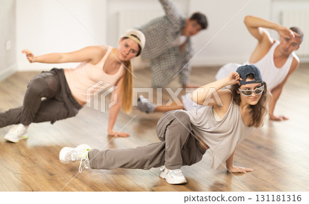 Girl and her students perform hip hop dance on one bent leg, movement in horizontal plane near floor 131181316