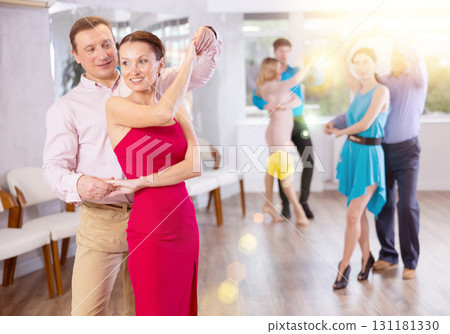 Smiling brunette in red dress practicing bachata with male partner 131181330
