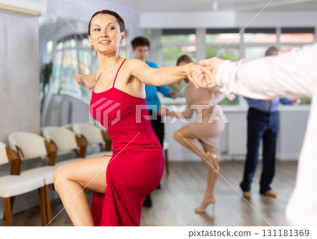 Happy woman enjoying active dancing in pair in dance studio Happy woman enjoying active dancing in pair in dance studio 131181369