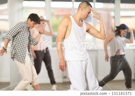 Young man standing performs basic hip hop movements in front of group of students Young man standing performs basic hip hop movements in front of group of students 131181371