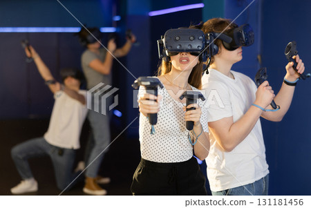 Young woman in VR glasses playing virtual game with handheld controllers 131181456