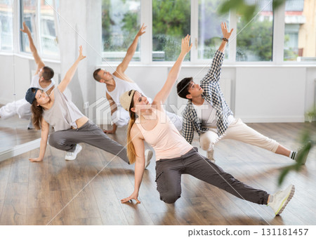 Girl and her students perform hip hop dance on one bent leg, movement in horizontal plane near floor Girl and her students perform hip hop dance on one bent leg, movement in horizontal plane near floor 131181457