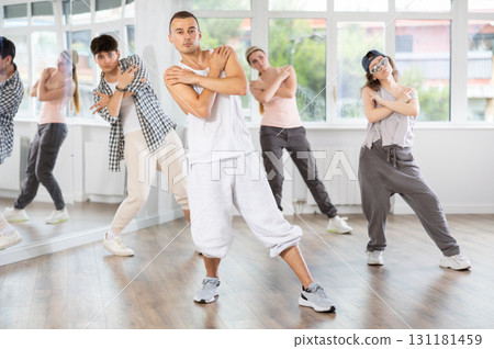 Young man standing performs basic hip hop movements in front of group of students Young man standing performs basic hip hop movements in front of group of students 131181459