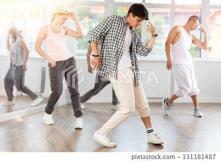 Young man standing performs basic hip hop movements in front of group of students Young man standing performs basic hip hop movements in front of group of students 131181487