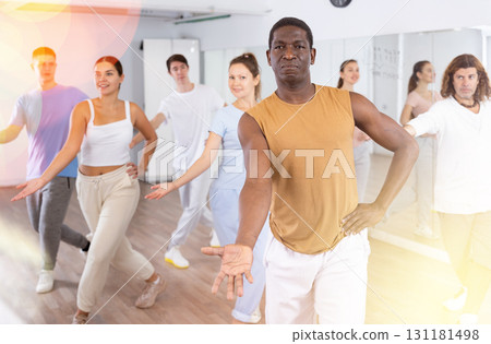 Cheerful multiracial people stretching out hand during dancing training in studio Cheerful multiracial people stretching out hand during dancing training in studio 131181498