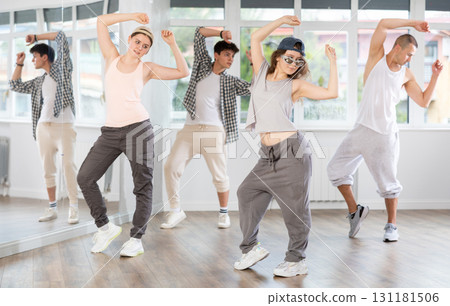 Young girl standing performs basic hip hop movements in front of group of students Young girl standing performs basic hip hop movements in front of group of students 131181506