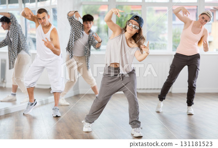 Young girl standing performs basic hip hop movements in front of group of students Young girl standing performs basic hip hop movements in front of group of students 131181523