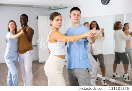 Group of diverse happy adult people dancing modern social dances in pairs at fitness studio 131181526