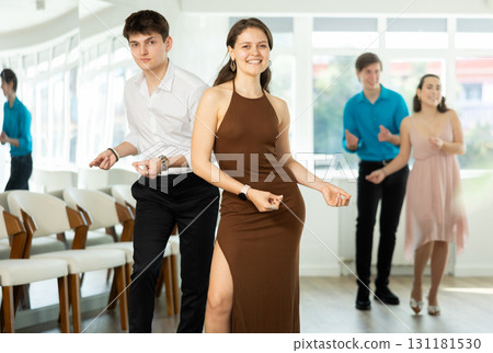 Couple in evening dresses enjoys pair dance boogie-woogie, interacting with each other on floor 131181530