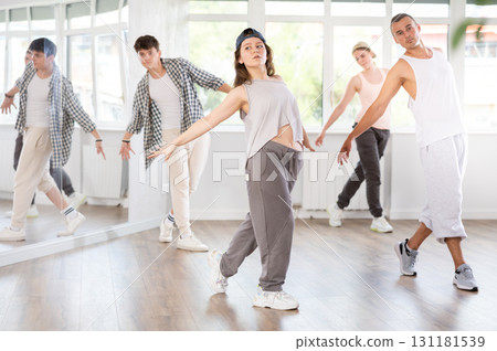 Dance group in casual clothes training to dance hip-hop and breakdance together in dance center Dance group in casual clothes training to dance hip-hop and breakdance together in dance center 131181539