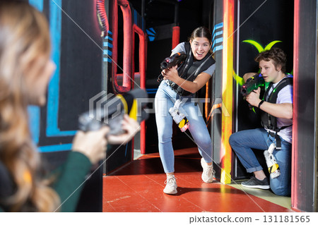 Positive girl holding laser pistol playing laser tag game with friends 131181565