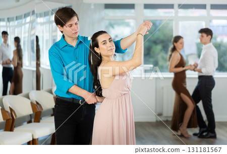 Young brunette practicing sensual bachata with guy in dance class Young brunette practicing sensual bachata with guy in dance class 131181567