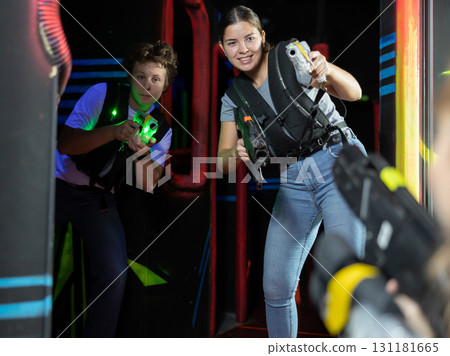 Boy and girl running and dodging while playing lasertag 131181665