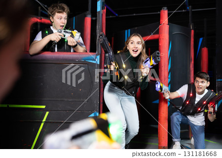 Portrait of excited people playing enthusiastically laser tag game two teams opposite each other in room Portrait of excited people playing enthusiastically laser tag game two teams opposite each other in room 131181668