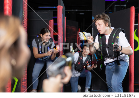 Portrait of positive man with laser gun having fun with her friends on lasertag arena Portrait of positive man with laser gun having fun with her friends on lasertag arena 131181672