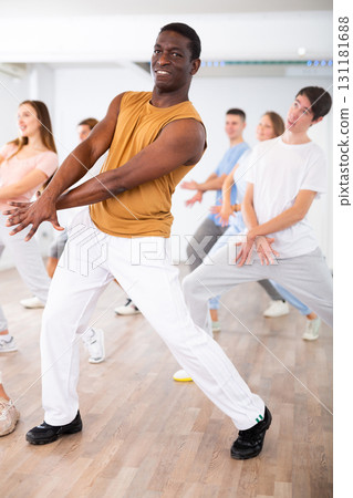 Happy multiracial men women of different ages performing dynamic energetic dancing movements in modern loft studio Happy multiracial men women of different ages performing dynamic energetic dancing movements in modern loft studio 131181688
