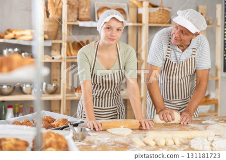 Man and woman bakers roll out dough with rolling pin 131181723