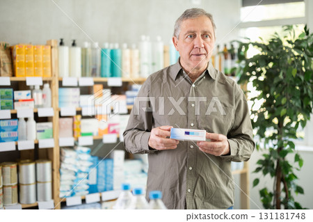 Older man examining box of ointment in pharmacy Older man examining box of ointment in pharmacy 131181748