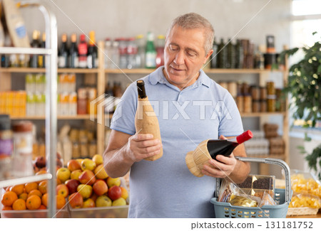 Senior man hold bottle and choose consider wine in store Senior man hold bottle and choose consider wine in store 131181752
