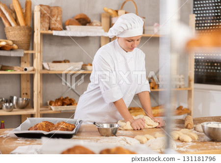 Young female apprentice baker kneading dough in bakery Young female apprentice baker kneading dough in bakery 131181796