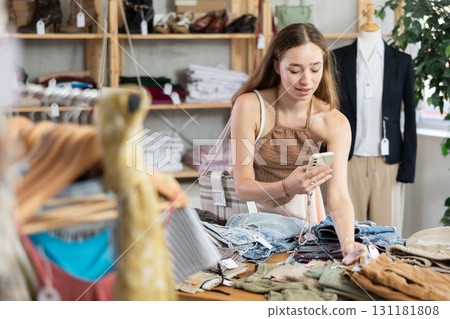 Selective young woman scanning QR-code on pantaloons in clothing store 131181808