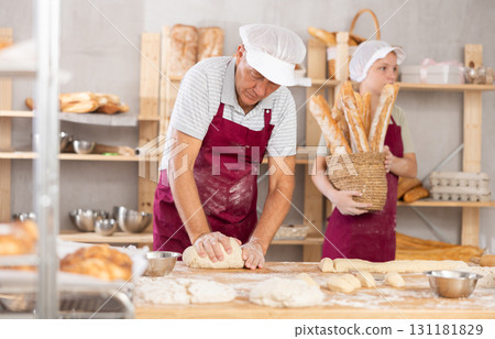 Professional aged baker kneading dough in artisan bakery Professional aged baker kneading dough in artisan bakery 131181829
