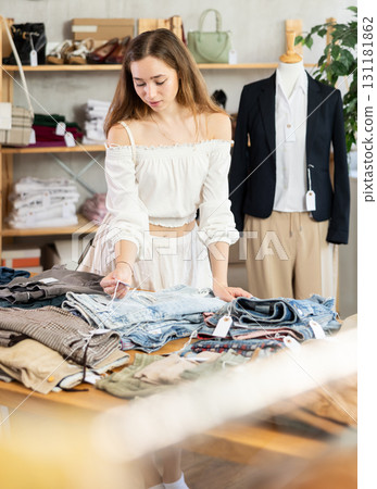 Selective young woman choosing pantaloons in clothing store Selective young woman choosing pantaloons in clothing store 131181862