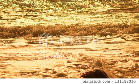Water Gold Waves: Golden ocean water sparkles and froths on surface during scenic golden hour. 131182030