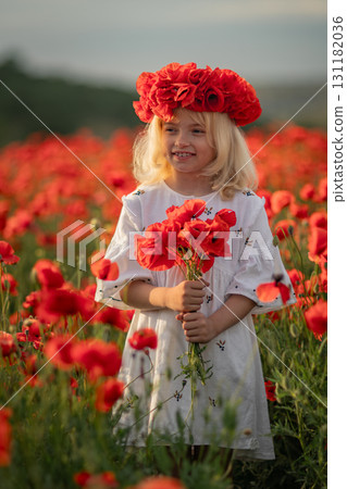 A young girl is standing in a field of red flowers, wearing a red headband. She is holding a bouquet of red flowers in her hand. Concept of innocence and joy 131182036