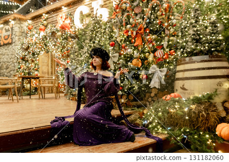 A woman in a purple dress is kneeling in front of a Christmas tree A woman in a purple dress is kneeling in front of a Christmas tree 131182060