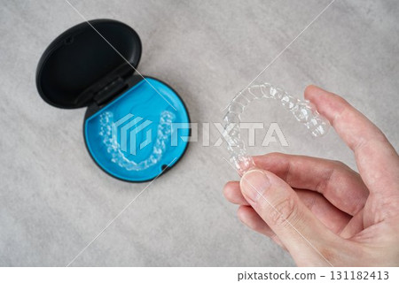 Image of a hand holding a case of orthodontic masks and aligners Image of a hand holding a case of orthodontic masks and aligners 131182413