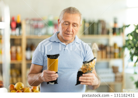 Mature man choosing package of pasta in grocery store Mature man choosing package of pasta in grocery store 131182431