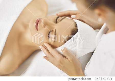 Female masseur making face skin care massage to a young girl in beauty spa salon. Female masseur making face skin care massage to a young girl in beauty spa salon. 131182445