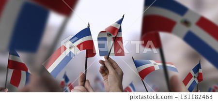 Dominicana flags in their hands on a blurred urban background Dominicana flags in their hands on a blurred urban background 131182463