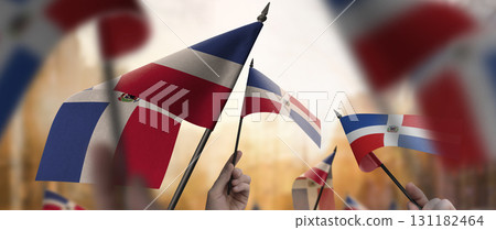 Dominicana flags in their hands on a blurred urban background 131182464