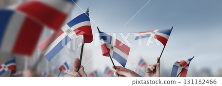 Dominicana flags in their hands on a blurred urban background 131182466
