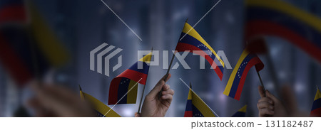 Venezuela flags in their hands on a blurred urban background Venezuela flags in their hands on a blurred urban background 131182487