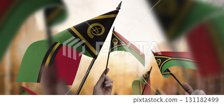 Vanuatu flags in their hands on a blurred urban background Vanuatu flags in their hands on a blurred urban background 131182499