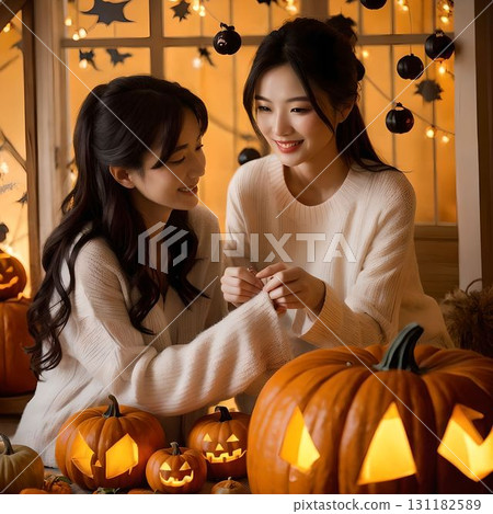 一男一女在室內微笑，周圍是萬聖節裝飾，點亮南瓜，營造出節日的秋季場景 131182589