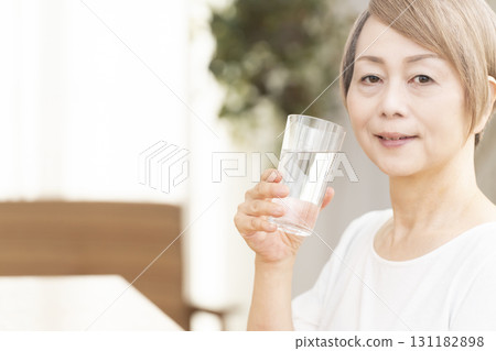 Senior woman drinking water in the living room Senior woman drinking water in the living room 131182898