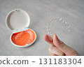Hand holding orthodontic aligner with orange and white case 131183304