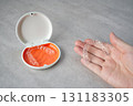 Hand holding orthodontic aligner with orange and white case 131183305