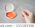 Hand holding orthodontic aligner with orange and white case 131183306
