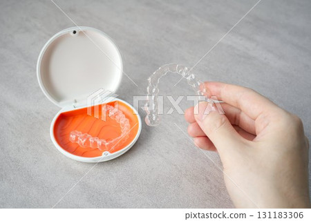 Hand holding orthodontic aligner with orange and white case 131183306