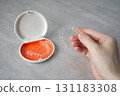 Hand holding orthodontic aligner with orange and white case 131183308