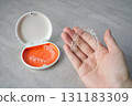 Hand holding orthodontic aligner with orange and white case 131183309