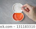 Hand holding orthodontic aligner with orange and white case 131183310