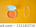 Orange and white case containing orthodontic aligners 131183716