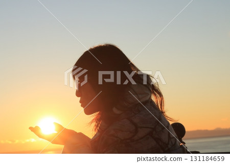 A woman holding the sunset in her palm 131184659